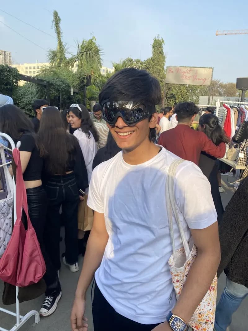 A guest in sunglasses at a rooftop edition, racks and stalls behind them in the evening light.